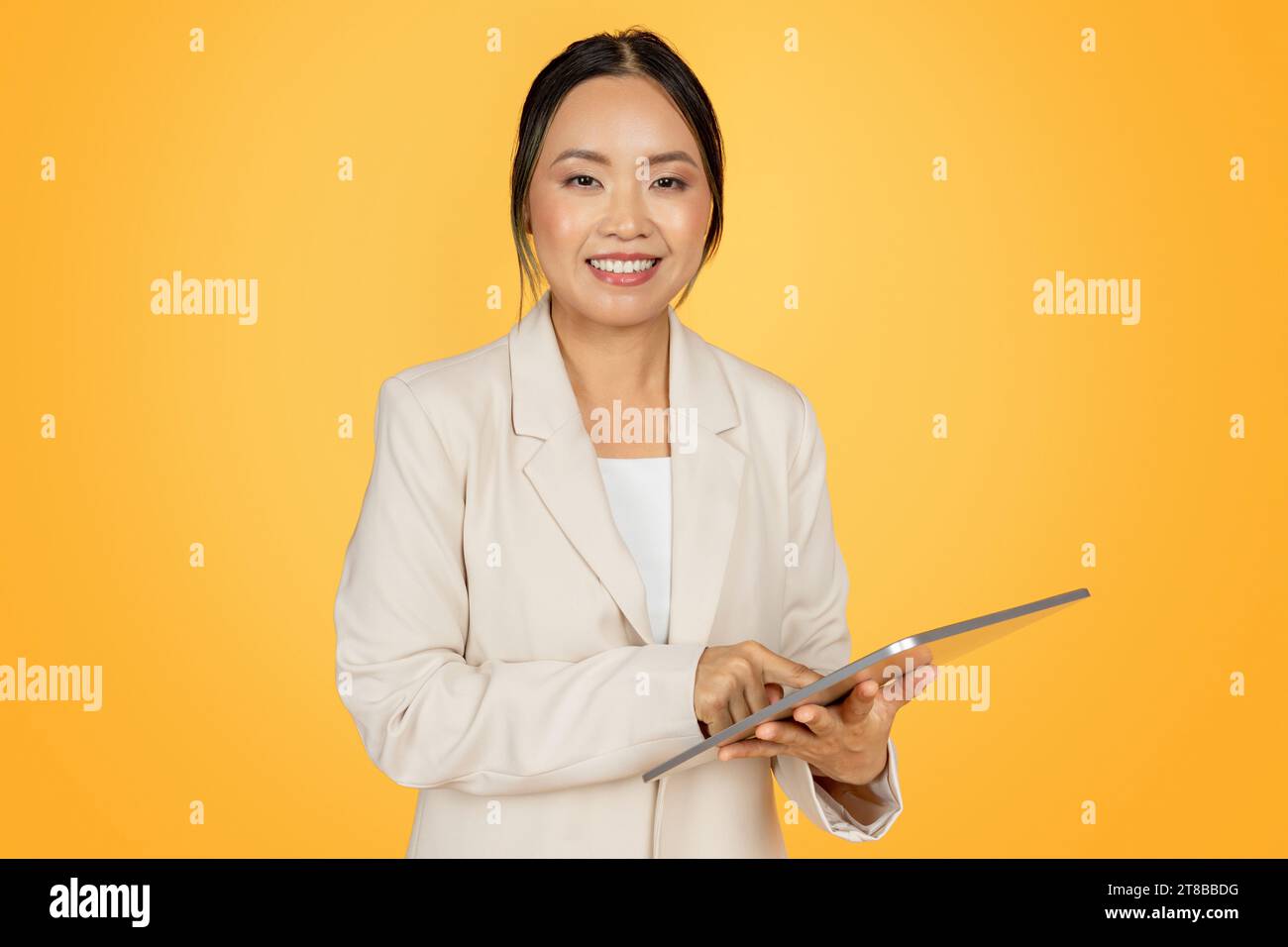Positive selbstbewusste junge japanische Geschäftsfrau im Anzug, mit Tablet Stockfoto