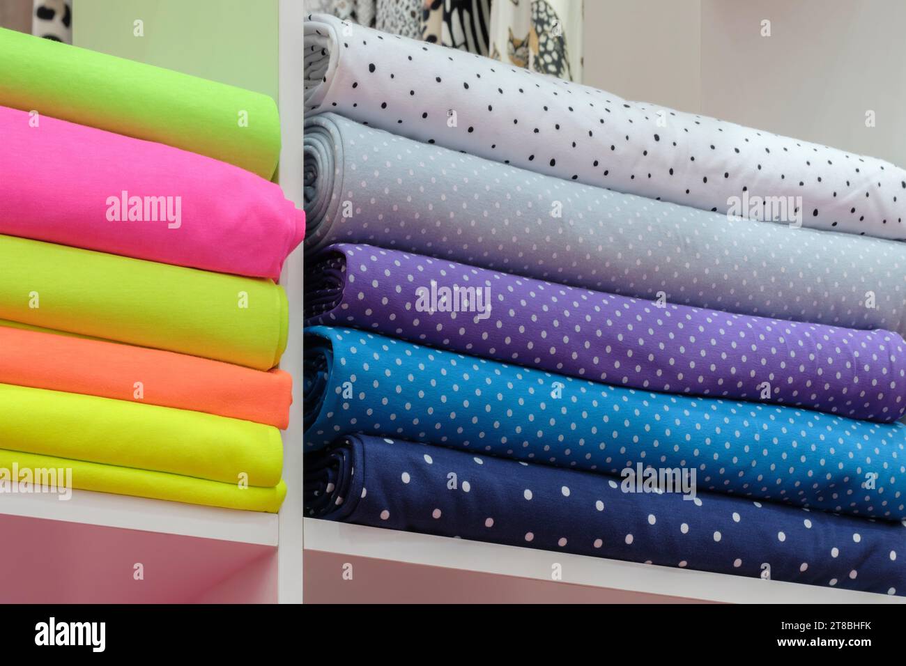 Regal mit einer großen Auswahl an farbenfrohen Stoffen. Bunte Bänder auf dem Regal im Laden. Textilindustrie Stockfoto