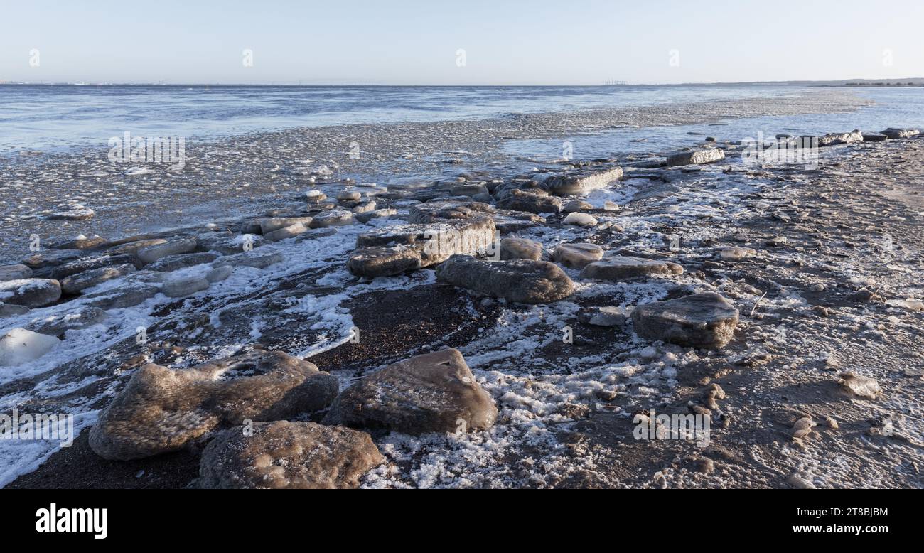 Schmelzende Eisschollen liegen an der gefrorenen Ostseeküste auf einem natürlichen Winterhintergrund Stockfoto