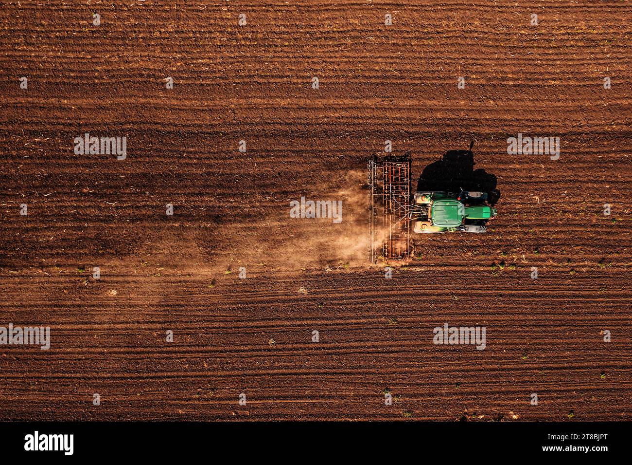 Traktor mit angebauter Deichsel, der vor der Aussaat die Bodenbearbeitung durchführt, Luftaufnahme vom pov der Drohne nach unten Stockfoto