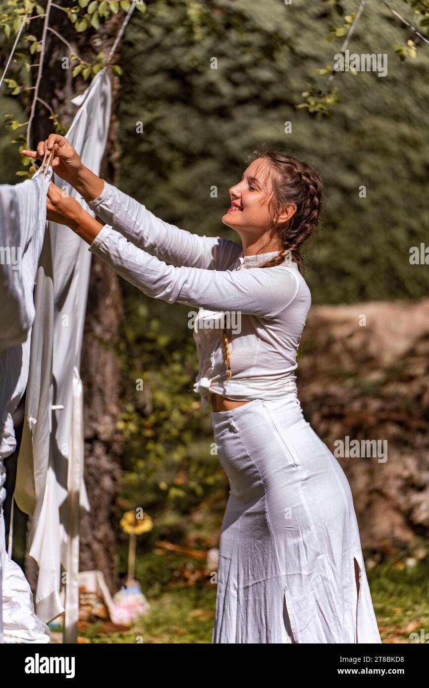 Eine junge Frau, die an einem sonnigen Tag im Garten Kleidung aufhängt. Stockfoto