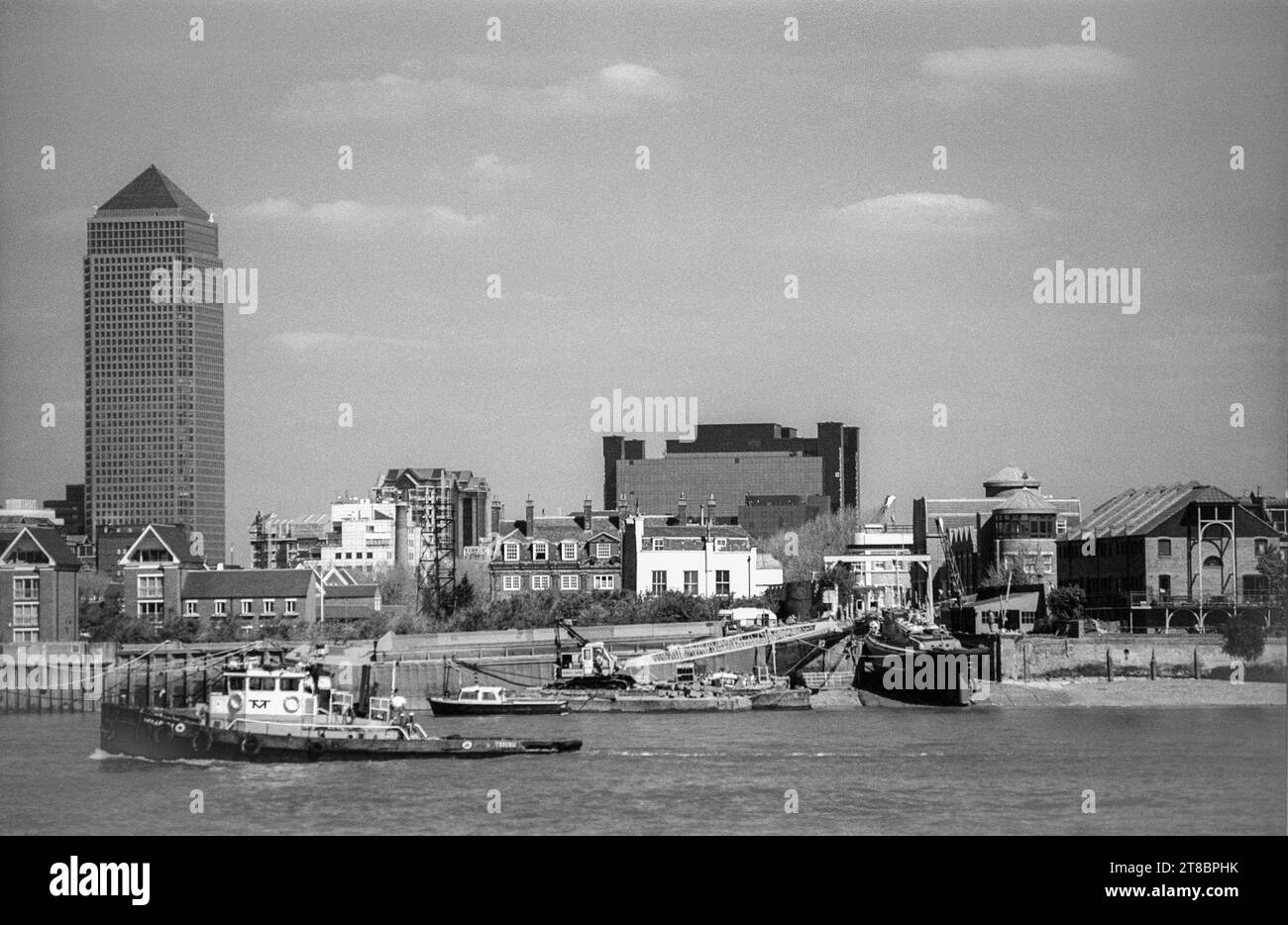 Schwarzweiß-Blick über die Themse aus der Nähe von Greenwich aus dem Archiv der 1990er Jahre. Das Boot auf der Slipway befindet sich am Ende der Ferry Street. Canary Wharf Büroentwicklung links. Stockfoto