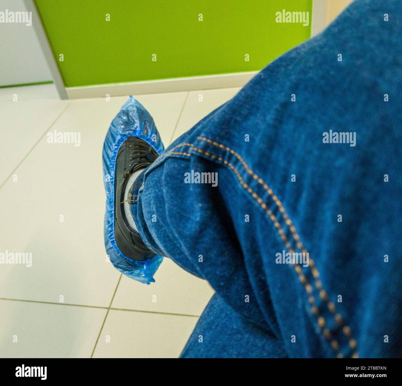 Die Person in der Jeans trägt Schuhüberzüge in der Klinik Stockfoto