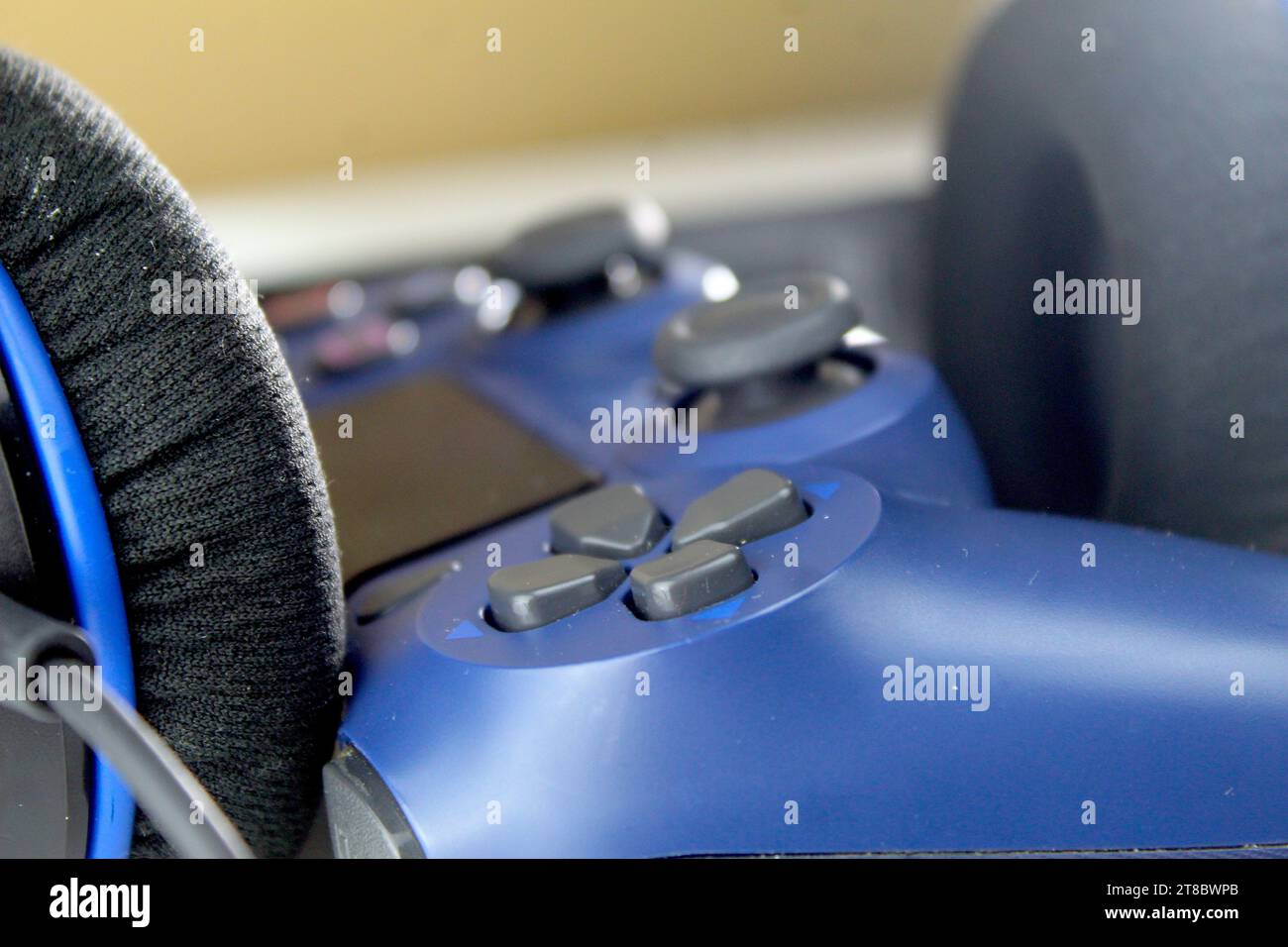 Ein Foto von einem dunkelblauen PlayStation-Spielekonsolen-Controller und zwei Kopfhörern auf einem weißen Tisch. Gamer. Stockfoto