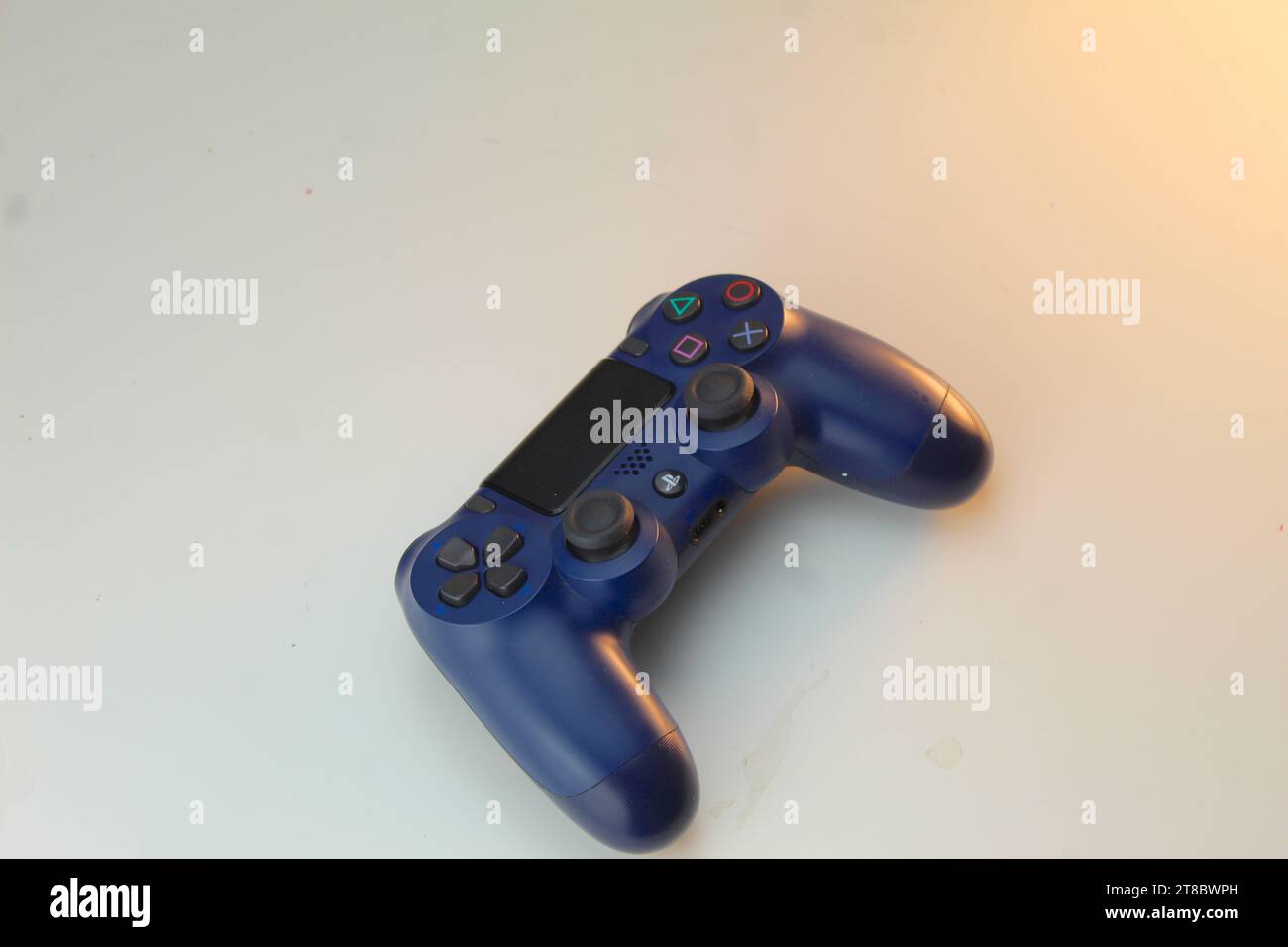 Ein Foto von einem dunkelblauen PlayStation-Spielekonsolen-Controller und zwei Kopfhörern auf einem weißen Tisch. Gamer. Stockfoto