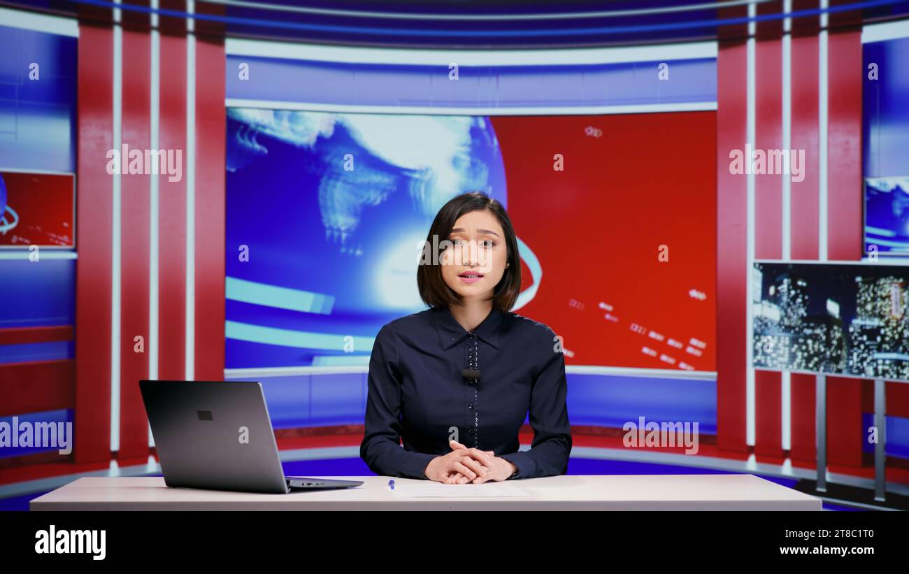 Asiatischer Moderator hostet Nachrichtensegment im Live-Programm und spricht alle Schlagzeilen im Newsroom an. Medienjournalistin präsentiert aktuelle Nachrichten und globale Ereignisse, Fernsehinhalte. Stockfoto