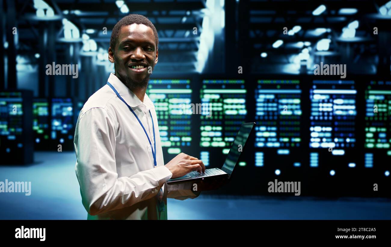 afroamerikanischer Ingenieur, der vernetzte Computer überprüft und ein Servernetzwerk erstellt. High-Tech-Einrichtung mit parallelem Computing, um komplexe Berechnungen durchzuführen und große Datenmengen zu verarbeiten Stockfoto