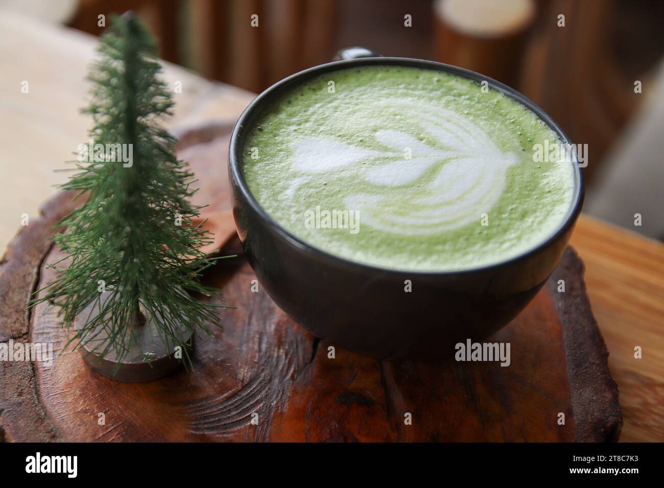 Tasse grüner Milchtee auf einem Holzständer Stockfoto