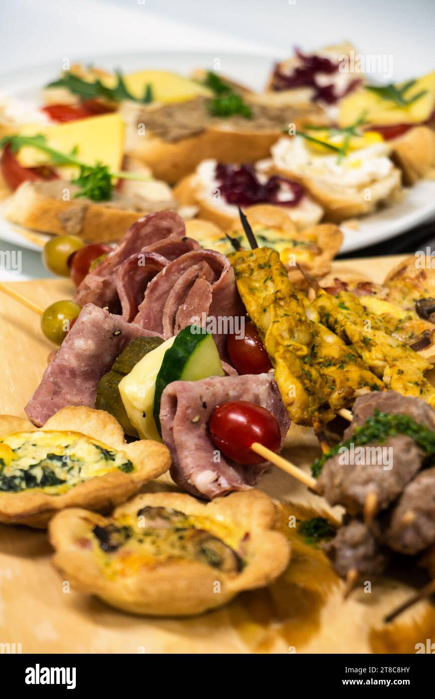 Leichte Snacks auf einem Spieß, Salami, Kirschtomaten, Hähnchenstreifen und herzhafte Torten Stockfoto