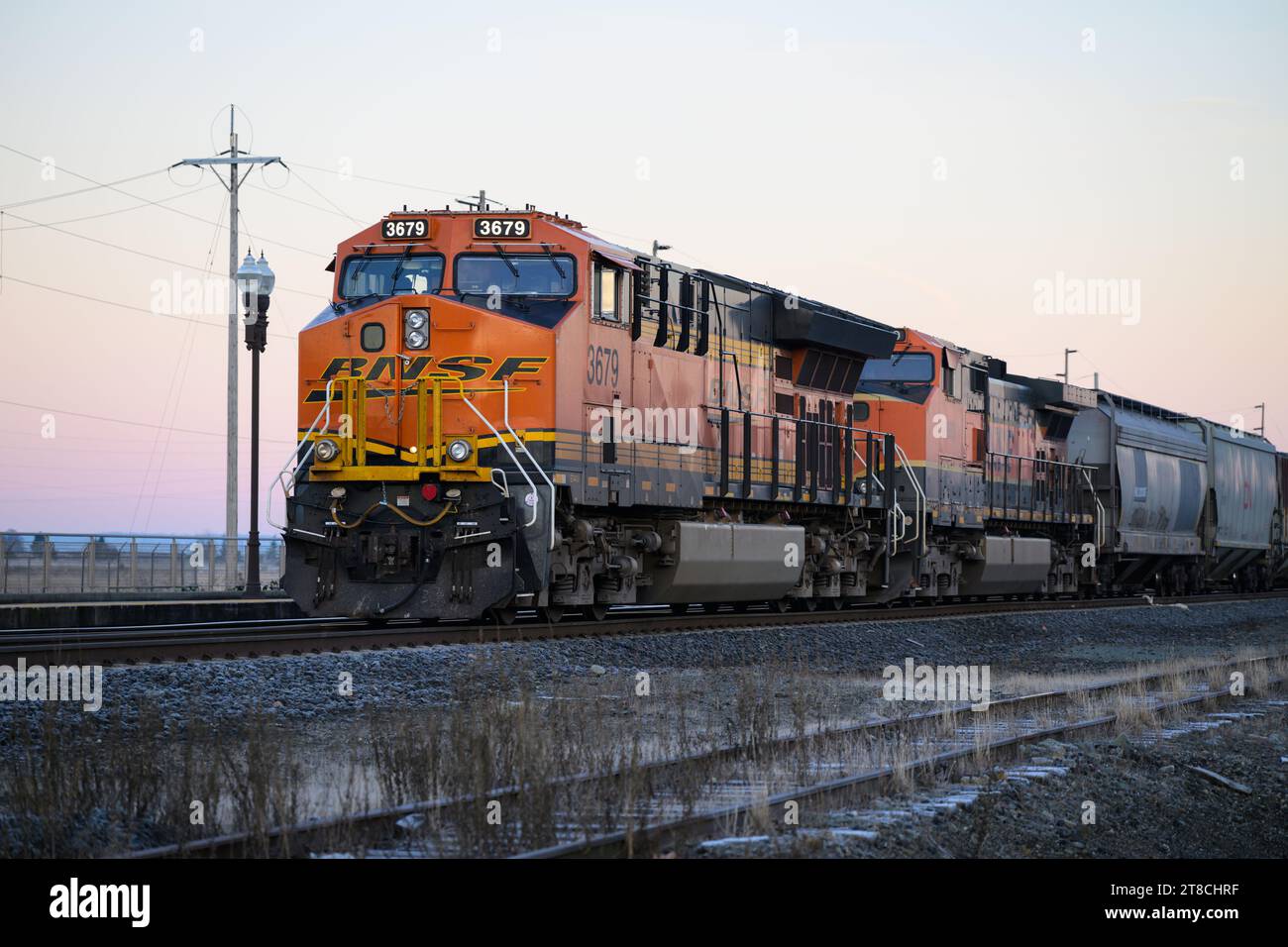 Stanwood, WA, USA – 17. November 2023; BNSF-Güterzug in Stanwood Washington bei Sonnenaufgang mit Logo auf orangefarbener Lokomotive Stockfoto