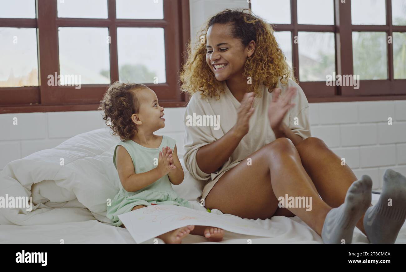 Mutter und Tochter lächeln und applaudieren im Bett Stockfoto