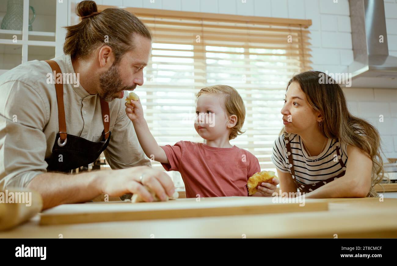 Glückliche Familie, die zusammen in der Küche isst, Mutter, Vater und Sohn essen Stockfoto