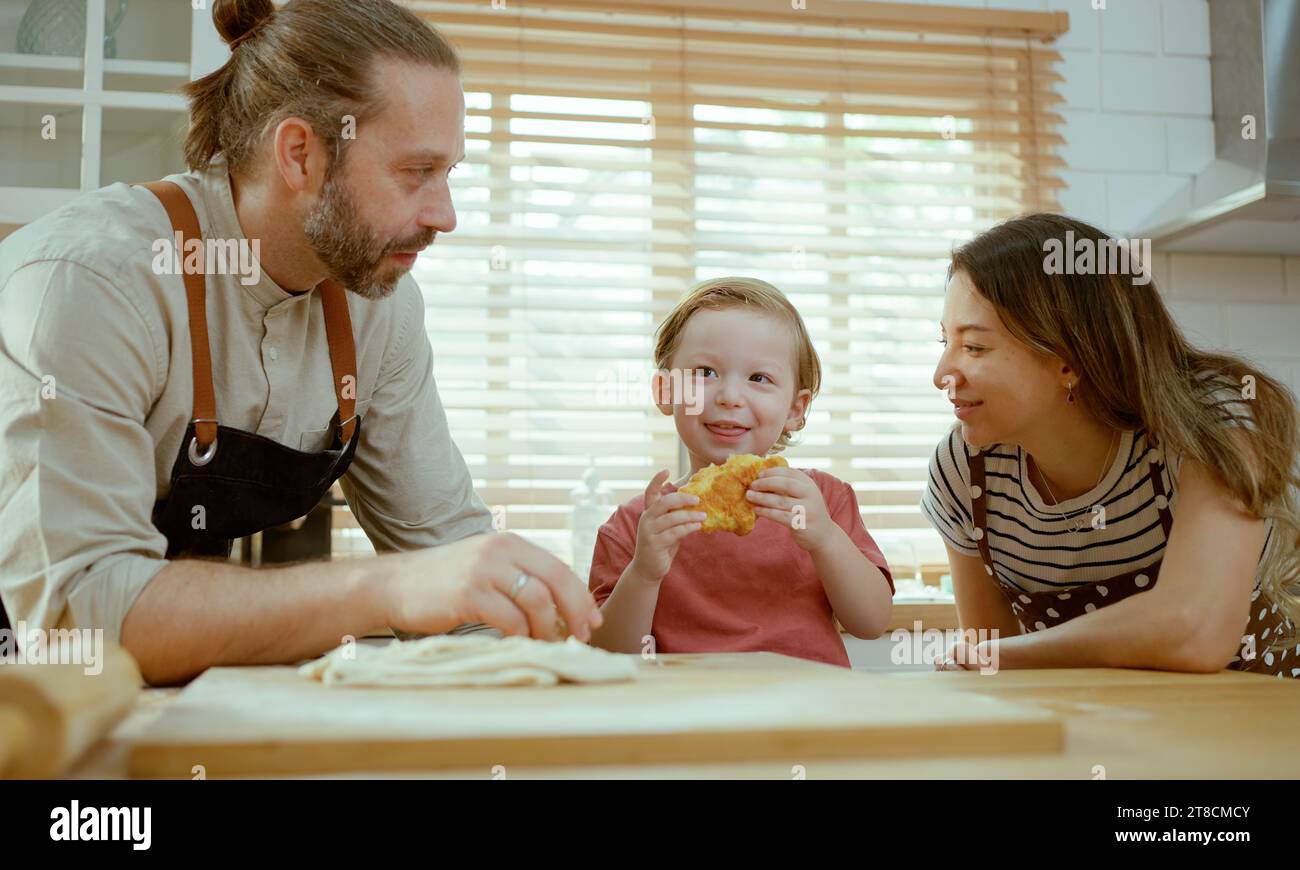 Glückliche Familie, die zusammen in der Küche isst, Mutter, Vater und Sohn essen Stockfoto