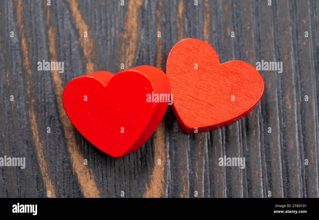 Zwei rote handgemachte hölzerne geschnitzte Herzen auf Holz Hintergrund, Paar Beziehung Valentinstag-Konzept Stockfoto