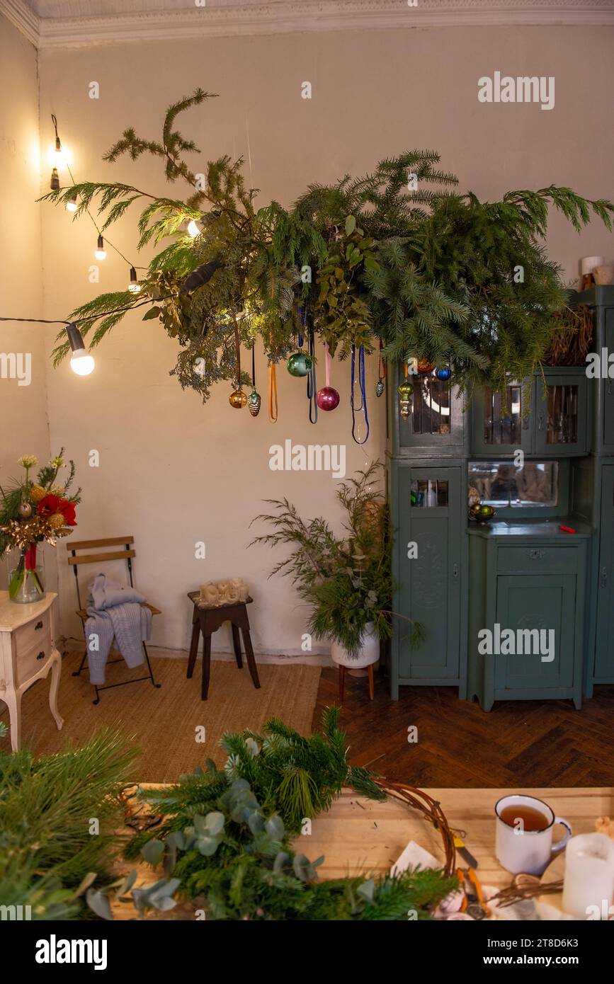 Authentisches, kreatives botanisches Weihnachtsdesign im rustikalen Stil. Hängende Girlande aus grünen Tannenzweigen mit Weihnachtskugeln an Bändern. Helles Vintage-G Stockfoto