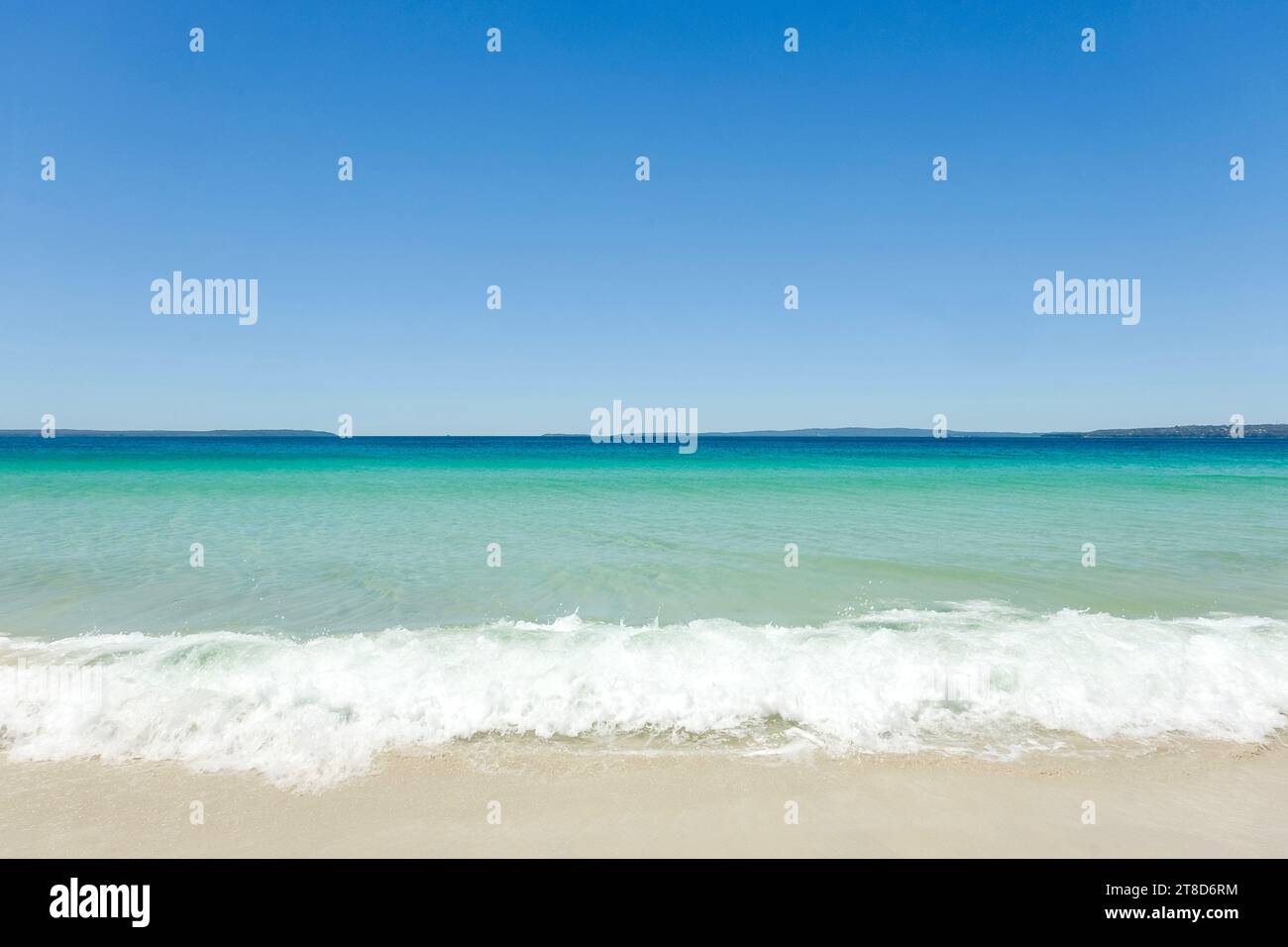 Klares türkisfarbenes Wasser, wolkenloser blauer Himmel und Meeresschaum an einem sonnigen Tag am Callala Beach in Shoalhaven – Jervis Bay National Park, NSW Stockfoto