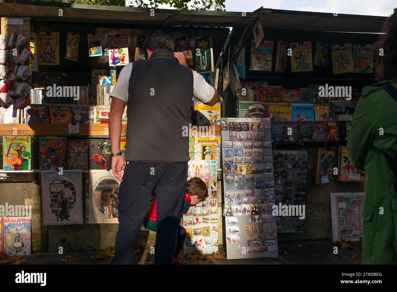 Die Leute schauen sich Bücher und Plakate an, während sie am 19. November 2023 an einem Bouquinisten-Stand vorbeilaufen, der antike Bücher und alte Plakate in der Nähe des seine-Ufers in Paris verkauft. Die Pariser Buchhändler, die größte Open-Air-Buchhandlung der Welt, die seit 450 Jahren am Ufer der seine tätig ist, weigern sich, von den Behörden zur Sicherheit der Eröffnungszeremonie der Olympischen Spiele 2024 in Paris bewegt zu werden. Die 240 Bouquinisten, die auf mehr als drei Kilometern der seine errichtet und zum UNESCO-Weltkulturerbe erklärt wurden, nutzen 900 grüne Boxen, um etwa 300.000 alte Bücher zu beherbergen Stockfoto