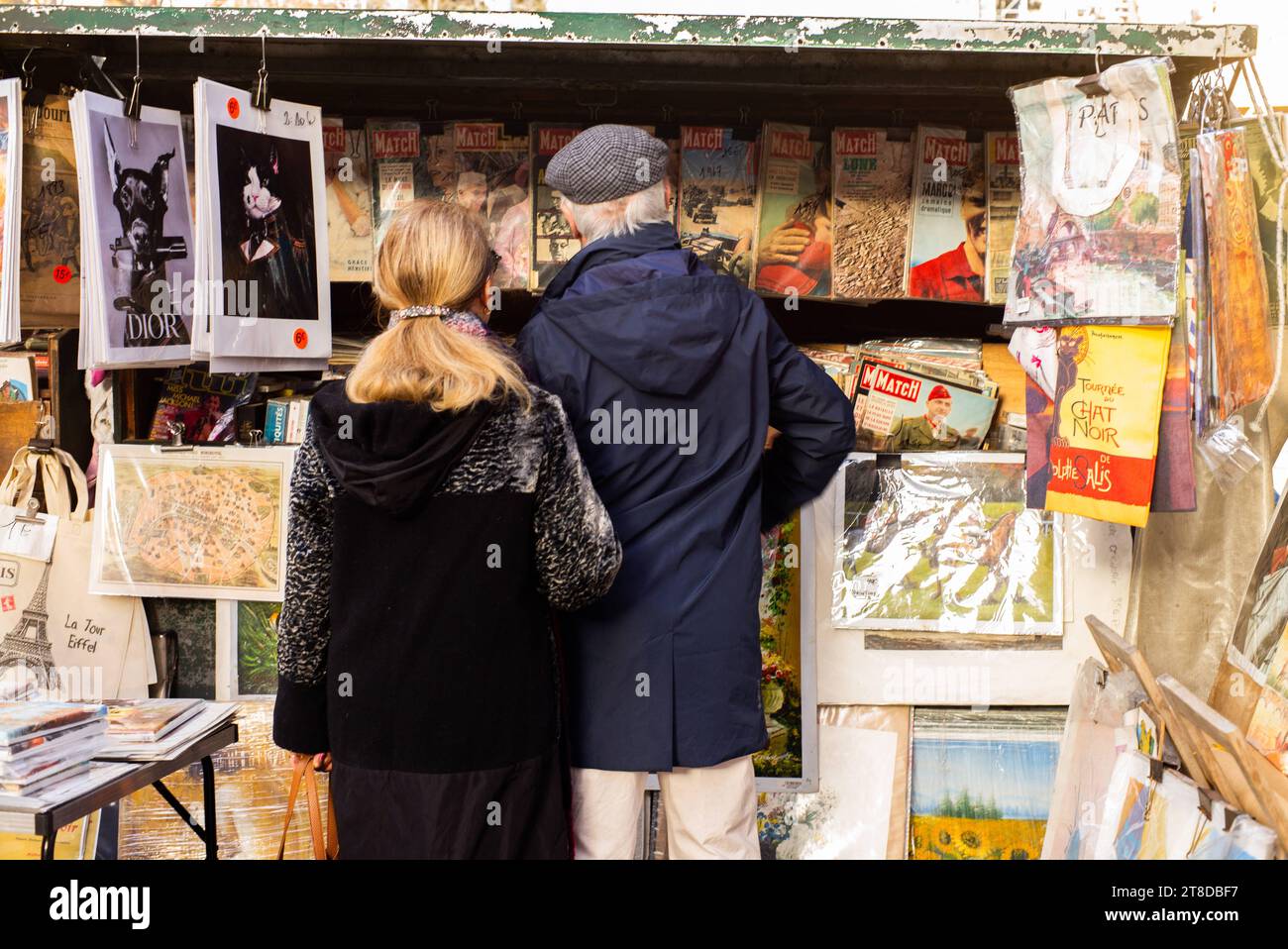 Die Leute schauen sich Bücher und Plakate an, während sie am 19. November 2023 an einem Bouquinisten-Stand vorbeilaufen, der antike Bücher und alte Plakate in der Nähe des seine-Ufers in Paris verkauft. Die Pariser Buchhändler, die größte Open-Air-Buchhandlung der Welt, die seit 450 Jahren am Ufer der seine tätig ist, weigern sich, von den Behörden zur Sicherheit der Eröffnungszeremonie der Olympischen Spiele 2024 in Paris bewegt zu werden. Die 240 Bouquinisten, die auf mehr als drei Kilometern der seine errichtet und zum UNESCO-Weltkulturerbe erklärt wurden, nutzen 900 grüne Boxen, um etwa 300.000 alte Bücher zu beherbergen Stockfoto