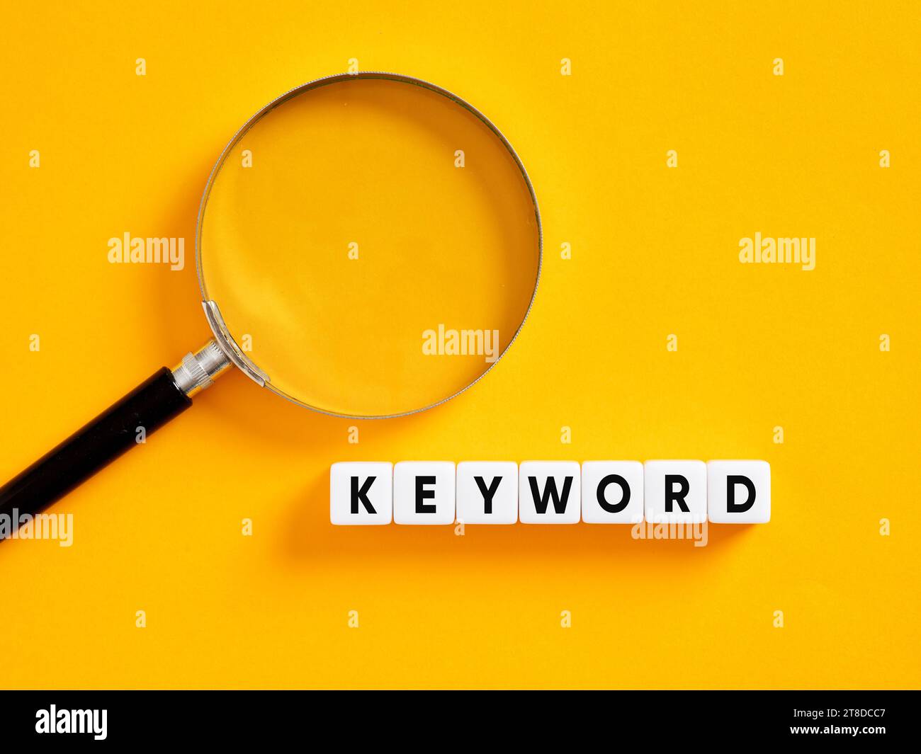 Suchbegriffe, suchbegriffe und Suchmaschinenoptimierung SEO-Konzept. Suche nach Schlüsselwörtern. Das Wort-Schlüsselwort auf weißen Würfeln mit einer Lupe. Stockfoto