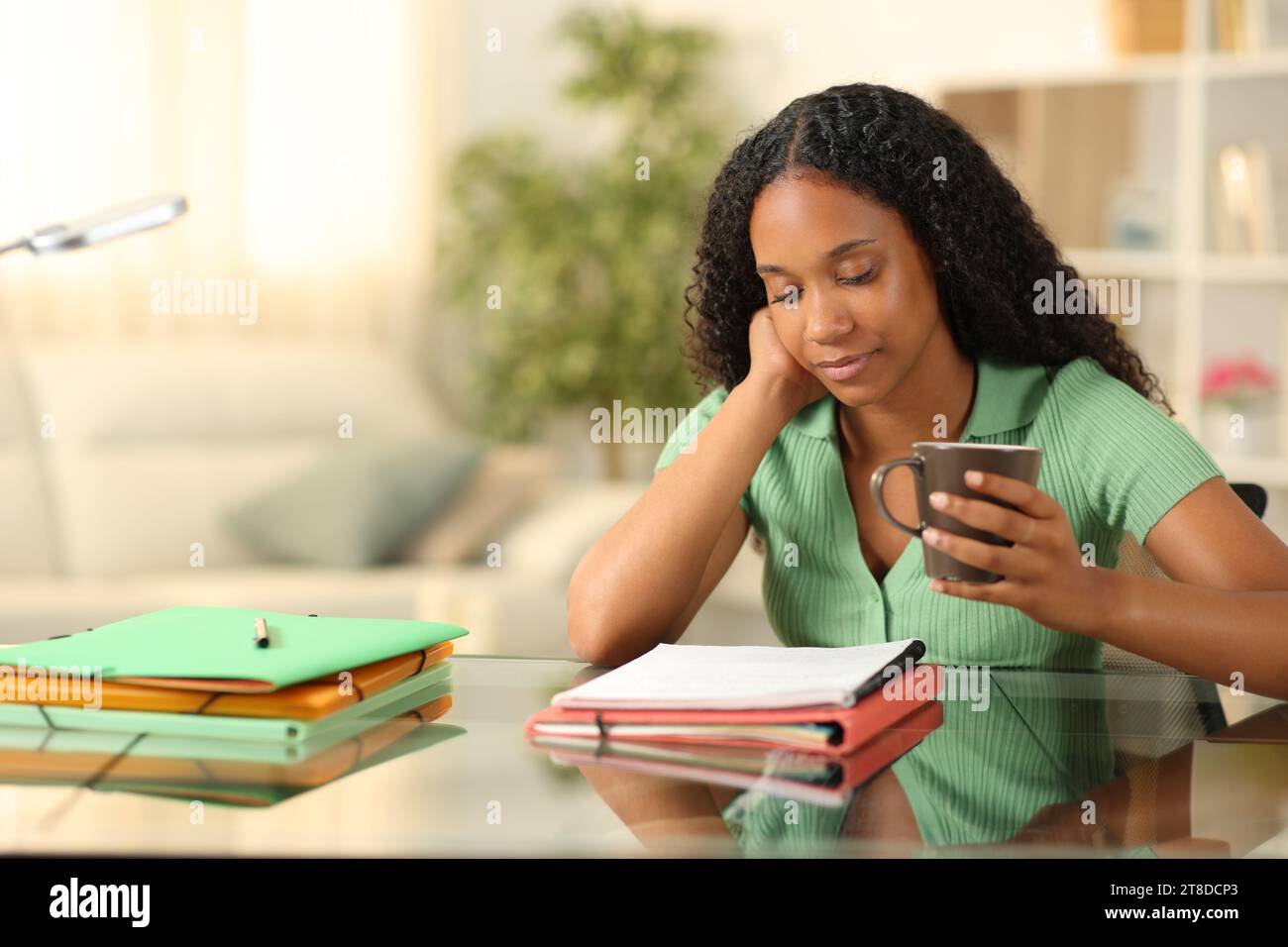 Schwarzer Student, der Notizen auswendig macht und Kaffee zu Hause hält Stockfoto