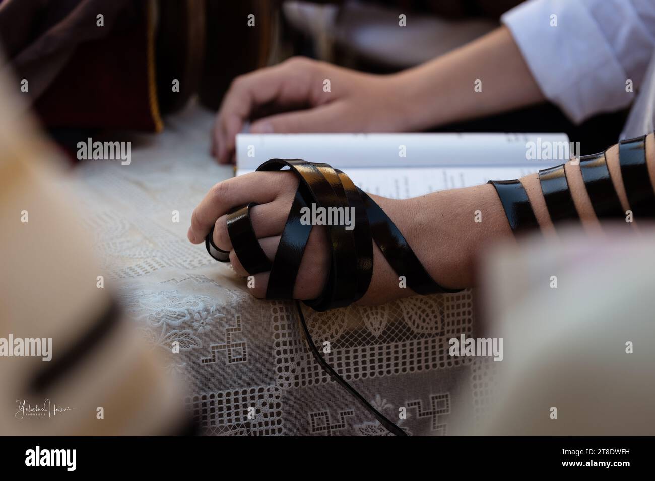 Ein Mann hält ein Siddur- oder jüdisches Gebetsbuch während der Morgengottesdienste in einer Synagoge in Israel. Stockfoto