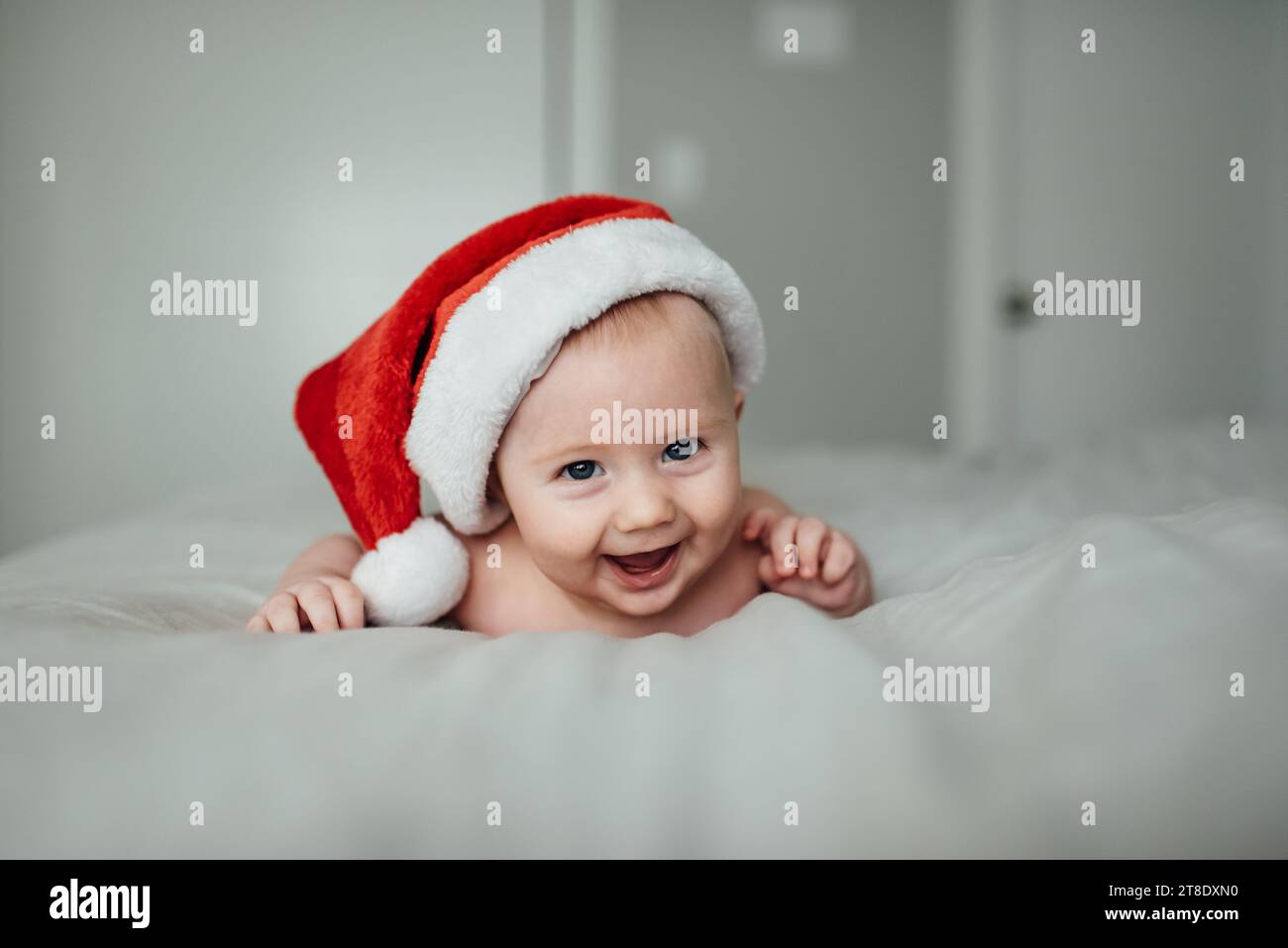 Nahaufnahme eines kleinen Jungen, der Weihnachtsmann-Hut trägt, während er lächelt Stockfoto