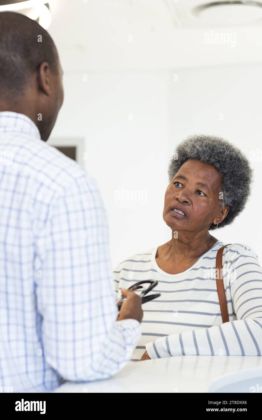 afroamerikanischer Arzt, der mit einer älteren Frau im Krankenhausempfang spricht Stockfoto
