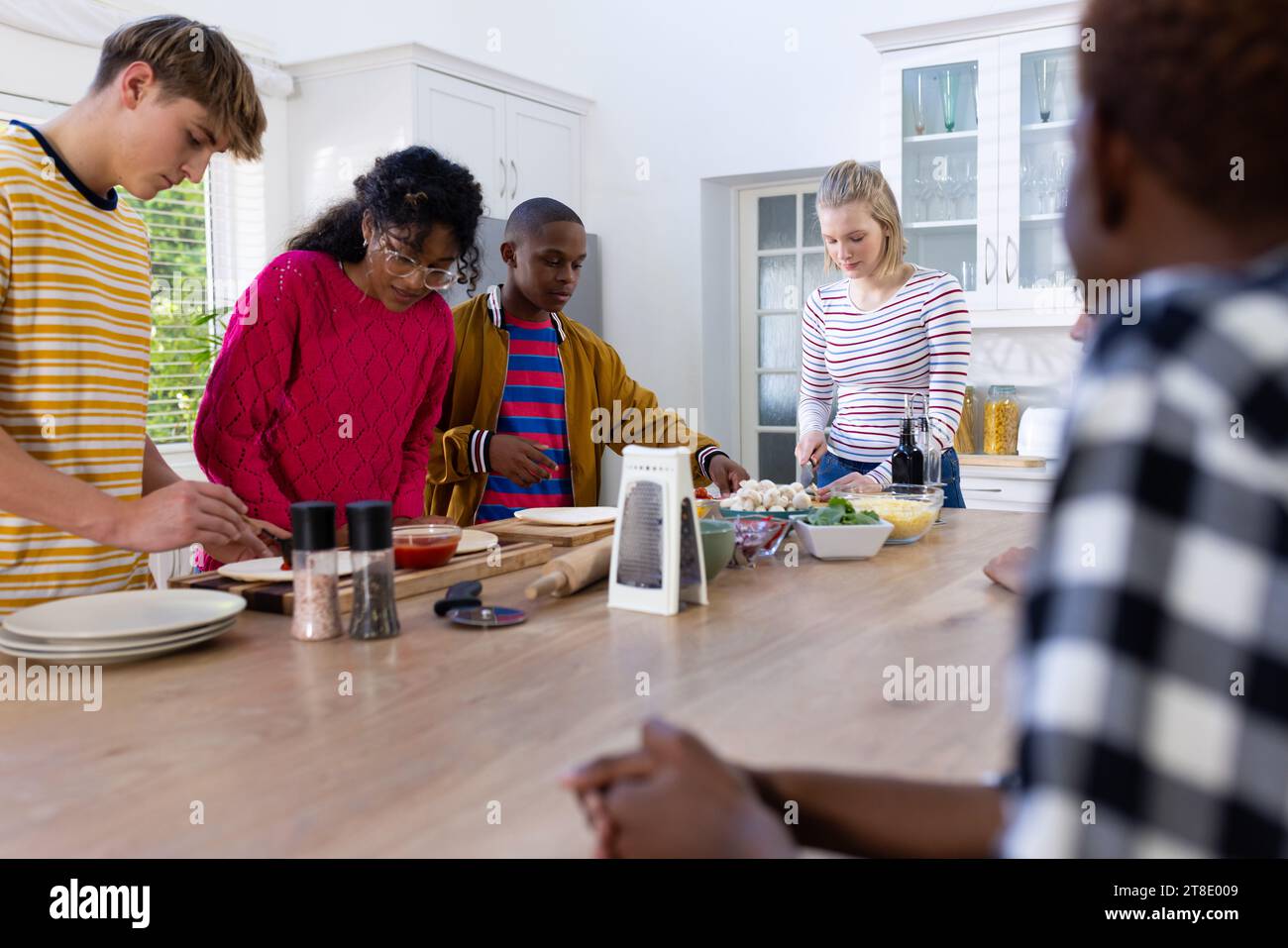 Glückliche, vielfältige Gruppe von Teenager-Freunden, die in der Küche kochen und Pizza machen Stockfoto