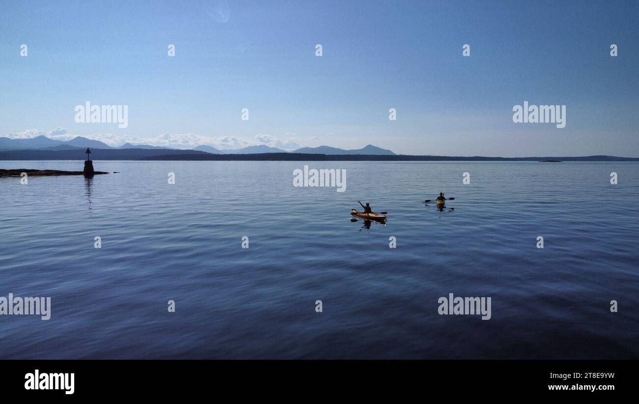 Junge Leute, die im Meer Kajak fahren. Endloser Blick auf die Vancouver Islands. Wunderschöne Farben Stockfoto