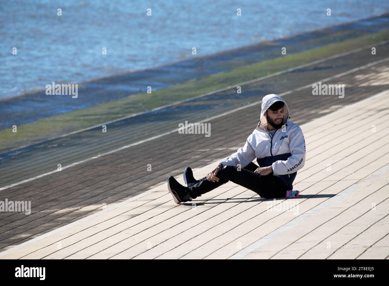 Ein junger Obdachloser ruht am Ufer des Flusses in Lissabon, Portugal Stockfoto