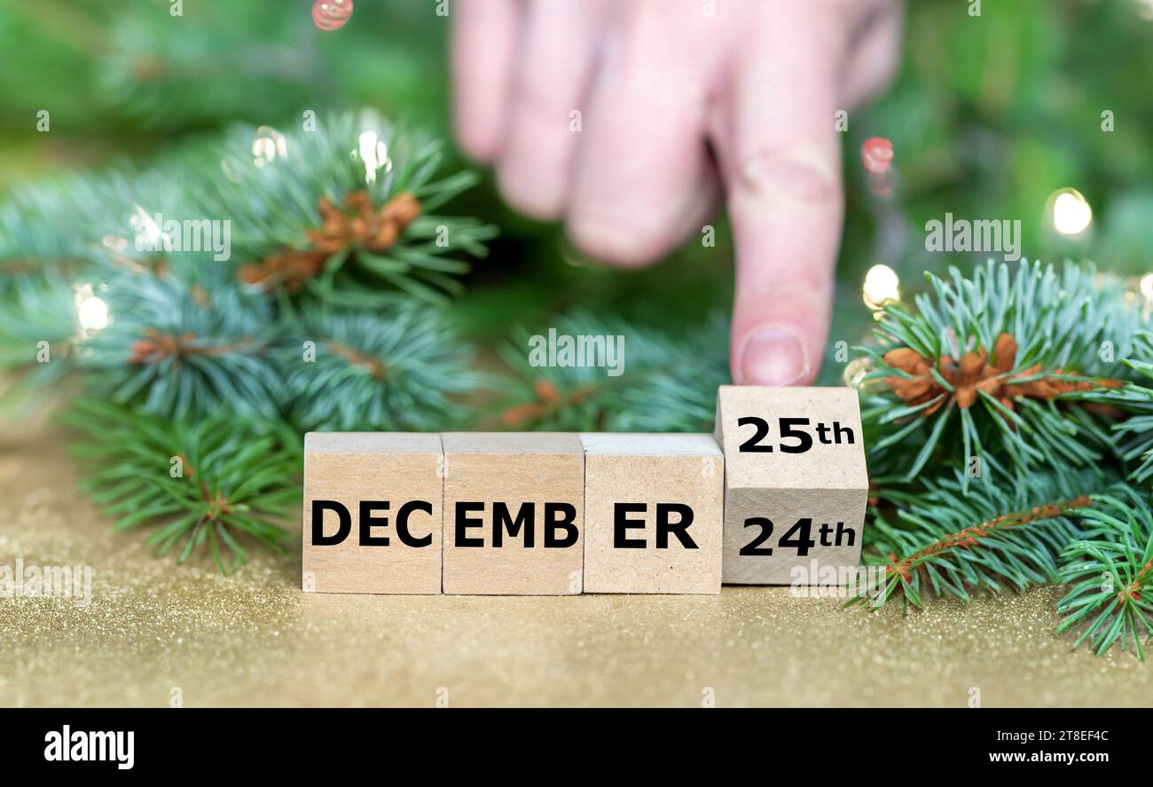 Die Hand dreht Holzwürfel und ändert das Datum „24. Dezember“ in „25. Dezember“. Stockfoto