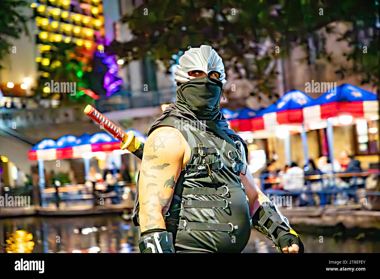 San Antonio, USA - 31. Oktober 2023: Die Menschen an Halloween spazieren entlang des San Antonio River Walk mit Kostümen bei Nacht mit beleuchteten Bäumen und ruhen sich aus Stockfoto