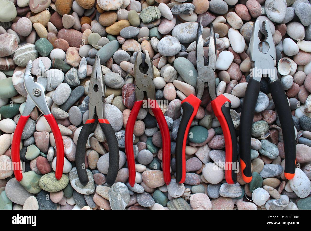 Gleitgelenkzangen, Nutzangen, Spitzzangen und Linesman-Zangen sind auf Größe angeordnet und auf Einem Steinhintergrund angeordnet Stockfoto