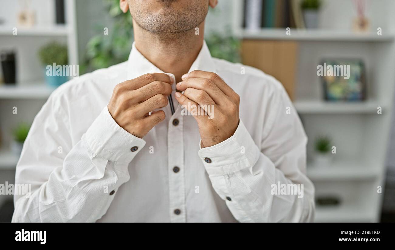 Entschlossener junger hispanischer Mann, der sich ernsthaft auf Erfolg konzentriert, in elegantem Hemd gekleidet, in Geschäftsarbeit am Schreibtisch eingetaucht. Kollegen porträtieren Stockfoto