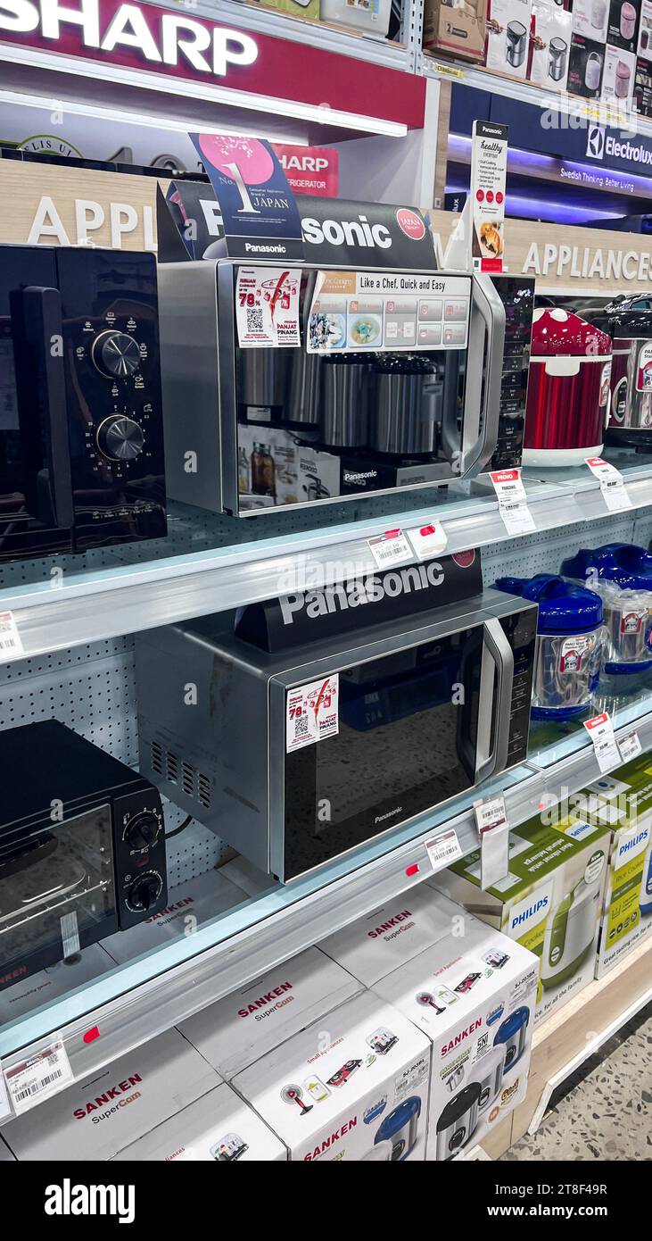 Mikrowellenherde stehen in einer Reihe auf verschwommenen Regalen in einem Supermarkt. Bekasi, Indonesien, 20. November 2023 Stockfoto