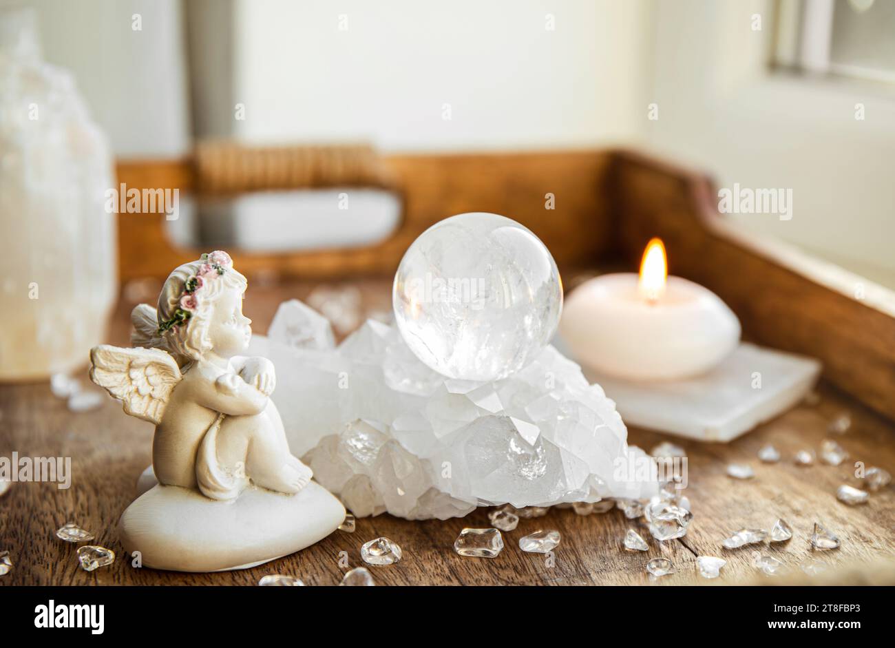 Spirituelles Engel-Botschaftskonzept. Kleine süße Engelsfigur sitzt drinnen neben Kristall-Edelsteinkugel. Stockfoto