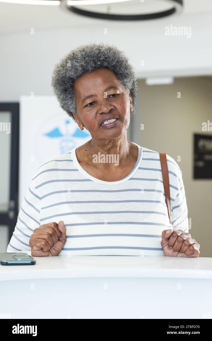afroamerikanische Seniorin mit Smartphone im Krankenhausempfang Stockfoto