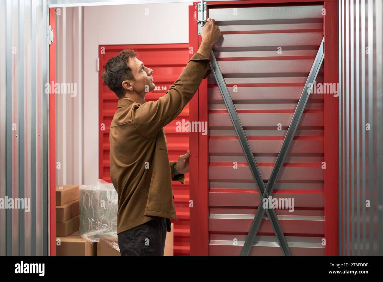Mann öffnet die Tür des Selbstspeichers, um Kisten mit Gegenständen darin zu platzieren Stockfoto