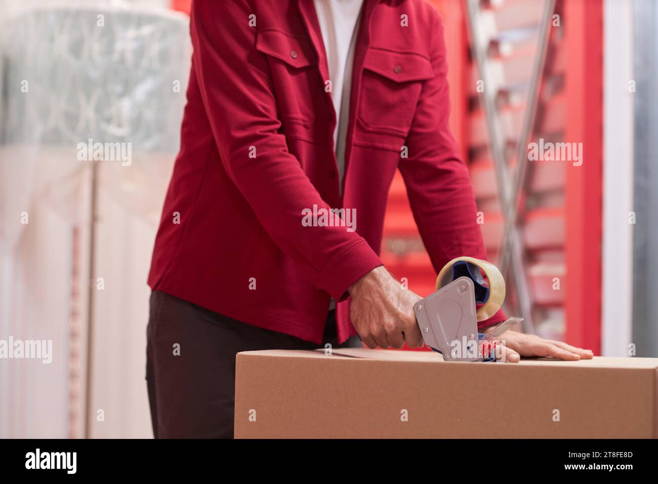 Zugeschnittenes Bild eines Mannes, der Karton in der Selbstaufbewahrungseinheit klebt Stockfoto