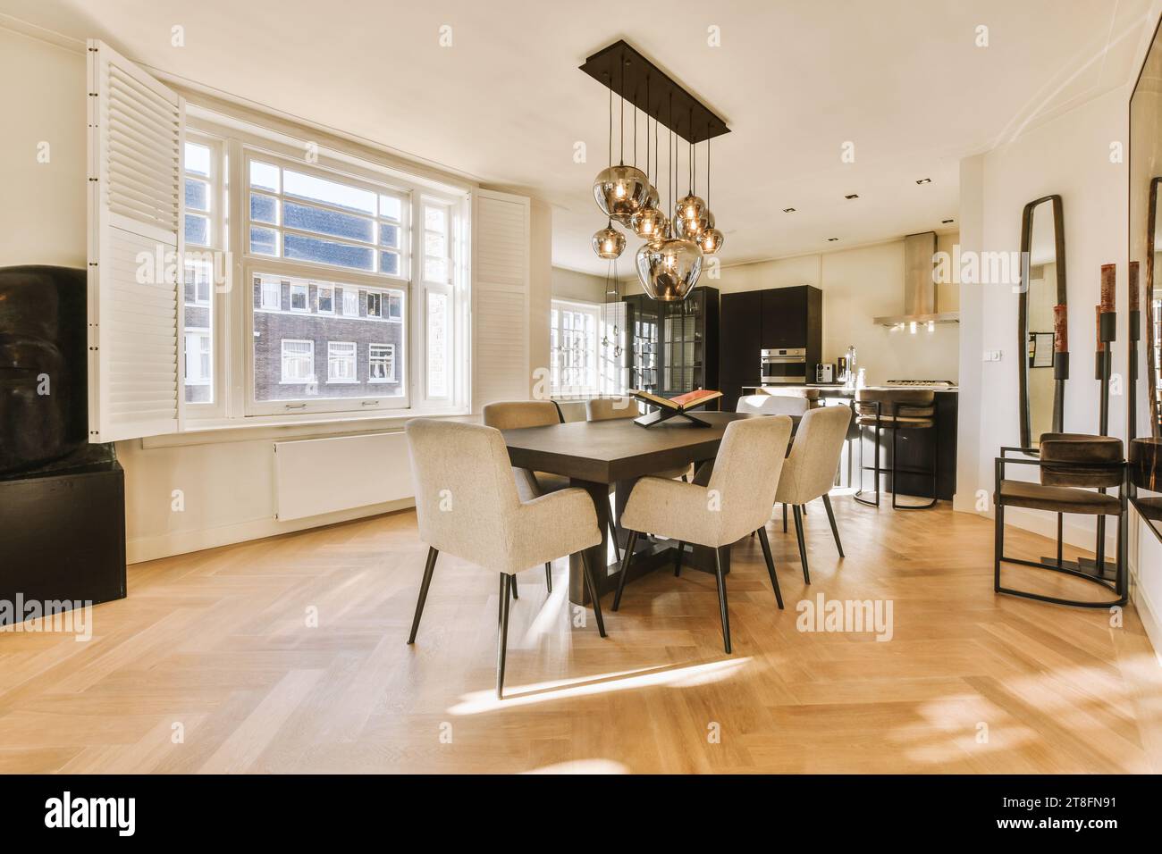 Stilvolle Pendelleuchten hängen über Esstisch und Stühlen im Speisesaal mit Fenster und weißen Wänden zu Hause Stockfoto