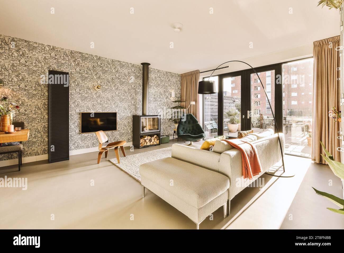 Komfortable Couch vor Fernseher und Kamin in geräumigem Wohnzimmer mit hellen großen Fenstern in einem modernen Zuhause Stockfoto