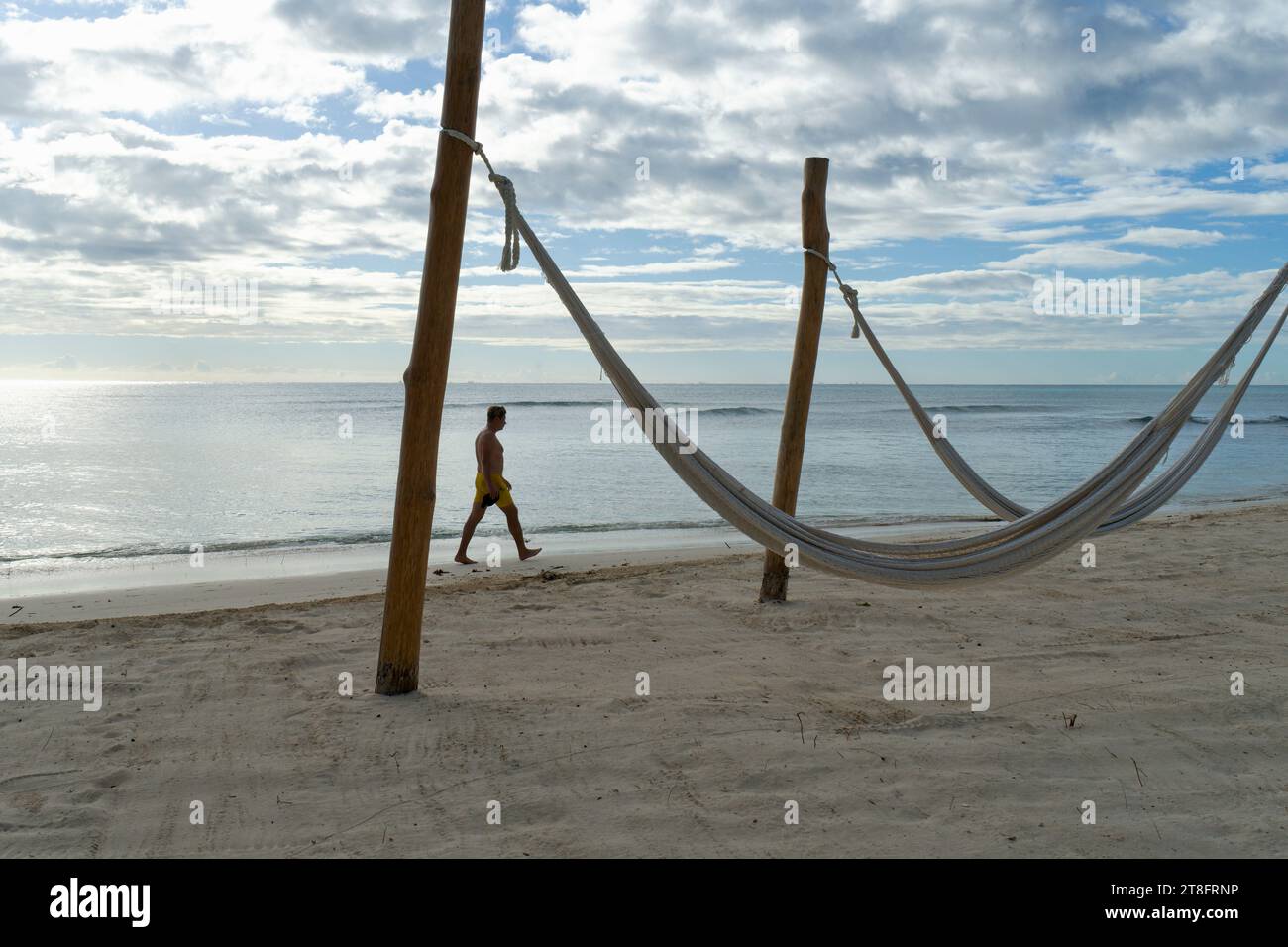 Nahaufnahme von Hängematten am tropischen Strand und einem nicht erkennbaren Mann, der entlang der Küste in Mexiko spaziert Stockfoto