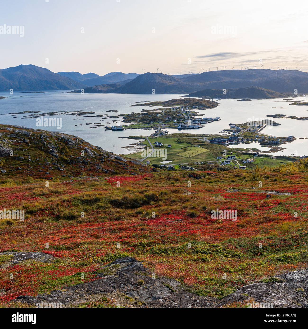 Wunderbarer Panoramablick vom Nordkollen bis hinunter nach Sommarøy und Kvaløya, mit dem Dorf und den Hafenanlagen und Windturbinen auf Hügeln Stockfoto