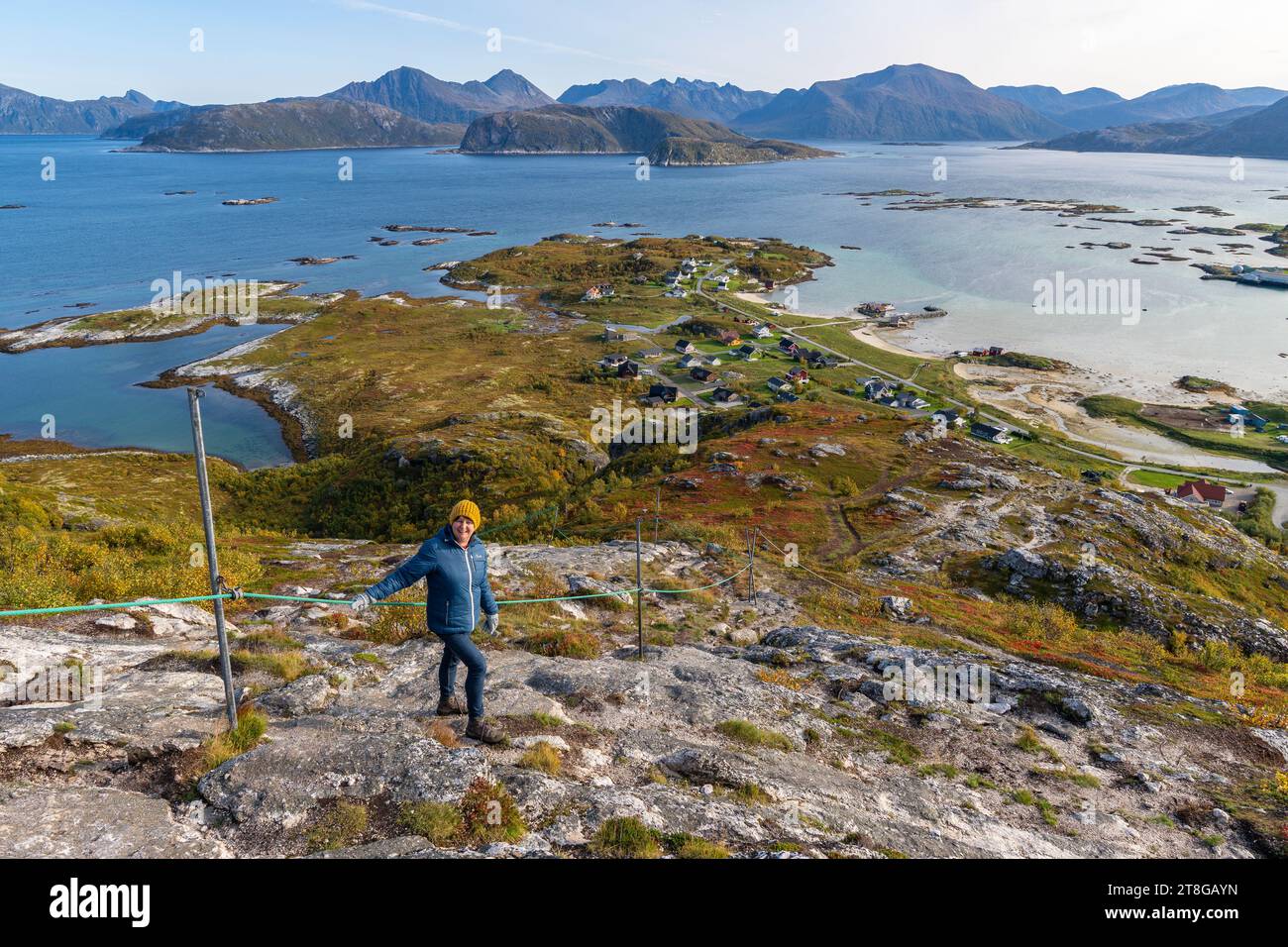 Blaubekleidete Frau Wanderung vom Nordkollen nach Sommarøy und Kvaløya, wunderbarer Panoramablick auf Insel, Dorf und Hafen Stockfoto