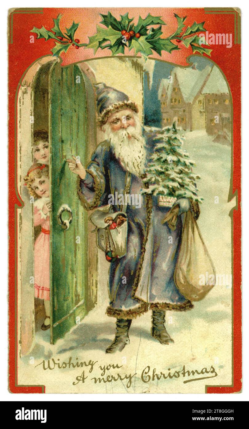 Originale viktorianische Weihnachtskarte - der Weihnachtsmann trägt ein blaues Gewand, trägt einen Sack mit Geschenken, trägt einen Weihnachtsbaum und klopft an die Tür eines Heims, wo aufgeregte Kinder auf seine Ankunft warten. Circa 1905, Großbritannien Stockfoto