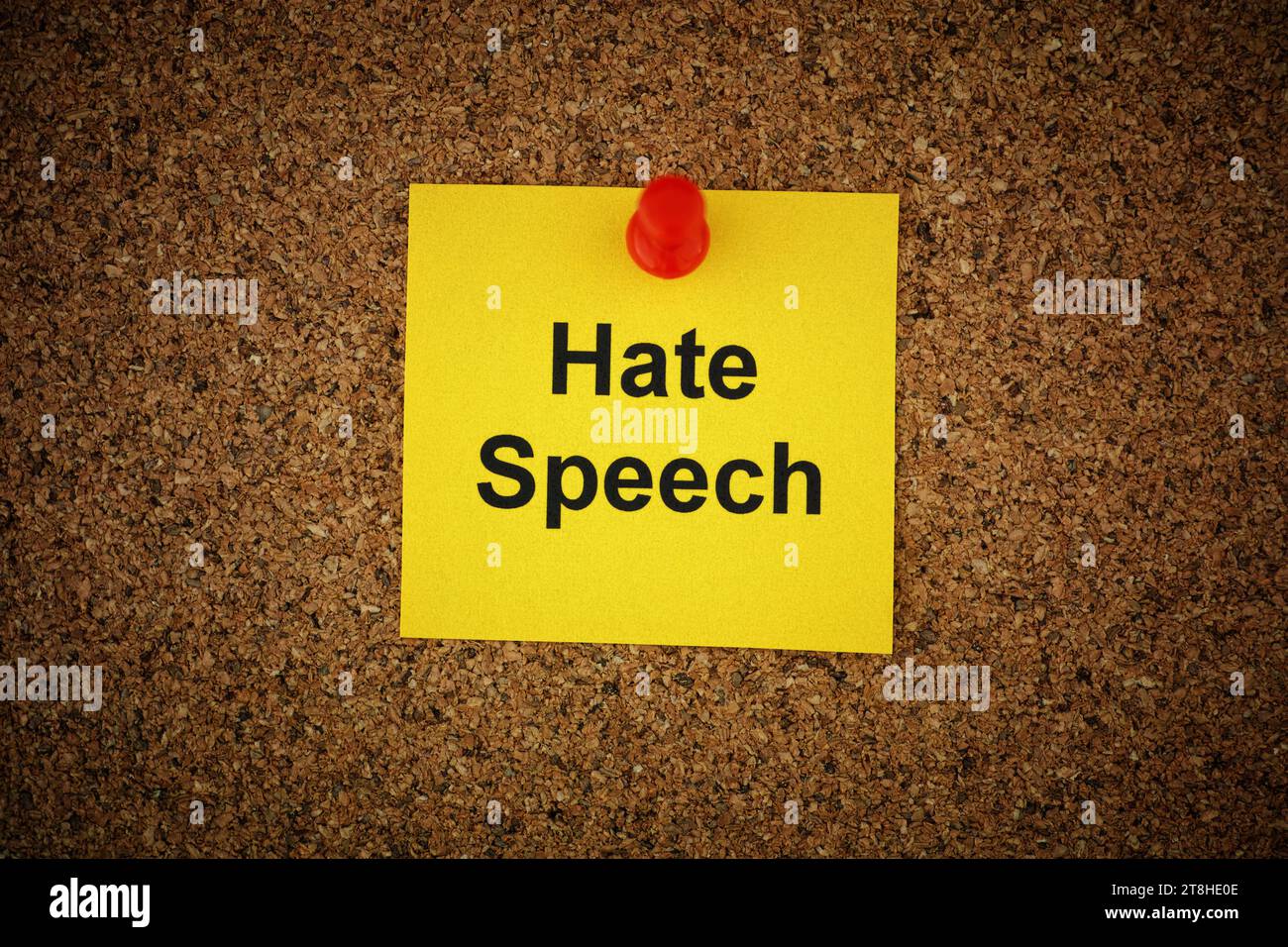 Ein gelber Zettel mit den Worten Hate Speech drauf, an ein Korkbrett geheftet. Nahaufnahme. Stockfoto