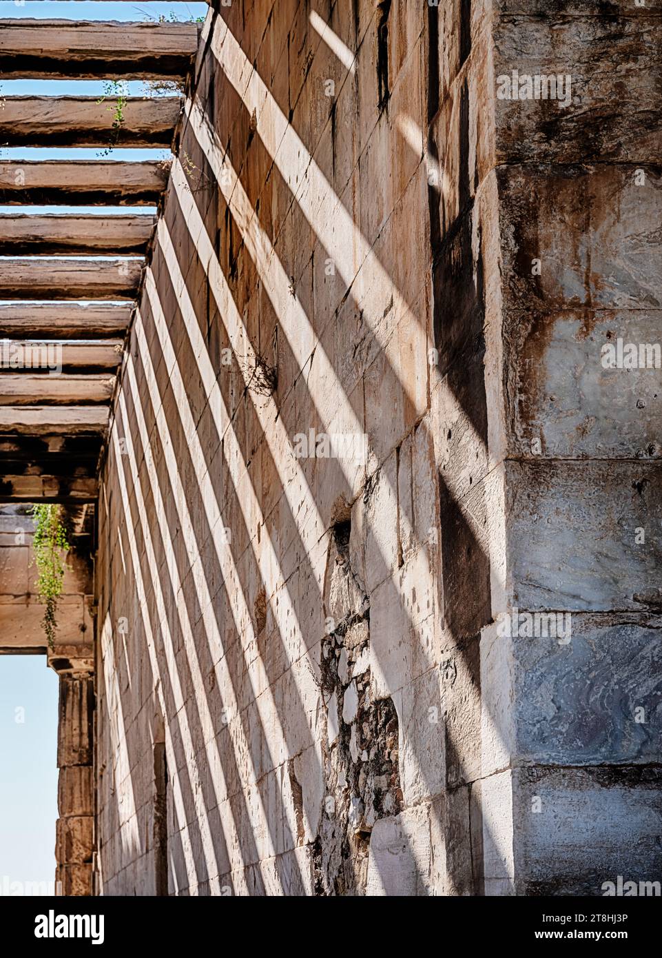 Abwechselnde Streifen von Sonnenlicht und Schatten erzeugen ein Muster an der Innenwand des Tempels des Hephaistos in der Athen Agora. Stockfoto