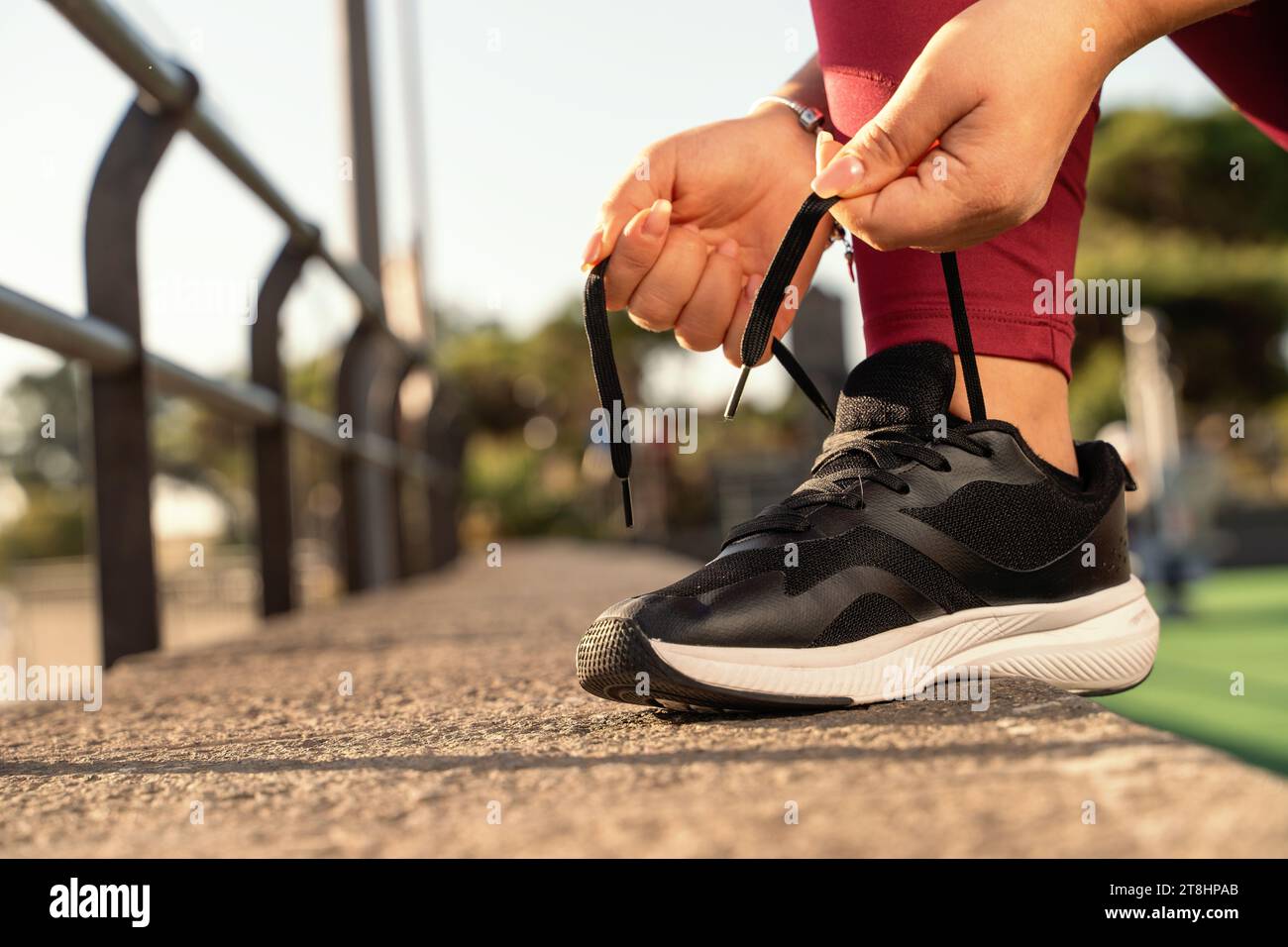 Nahaufnahme einer Frau, die ihre Laufschuhe bindet, bereit ist, ihr Workout zu beginnen, und hebt hervor, wie wichtig richtige Kleidung für körperliche Aktivität ist Stockfoto