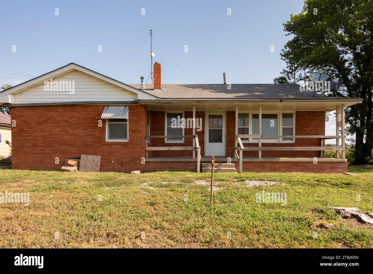 Die Vorderseite und der Eingang zu einem alten Bauernhaus aus Backstein zum Verkauf im Fernen Westen von Kansas, USA. Stockfoto