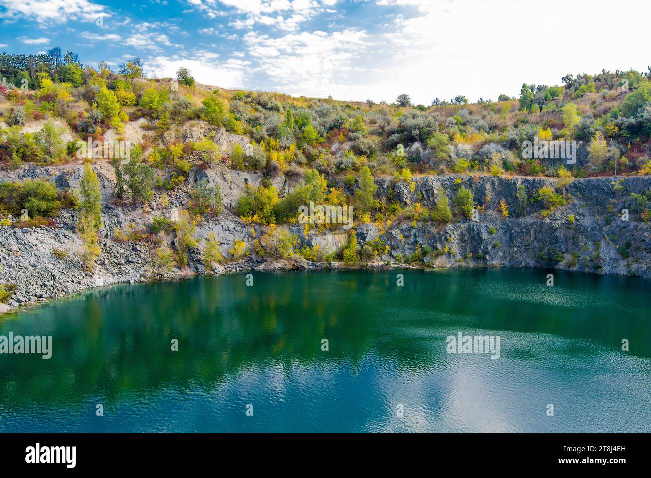 Überfluteter und verlassener Granitsteinbruch mit klarem türkisfarbenem Wasser. Sonniger Herbsttag. Drohne. Luftaufnahme Stockfoto